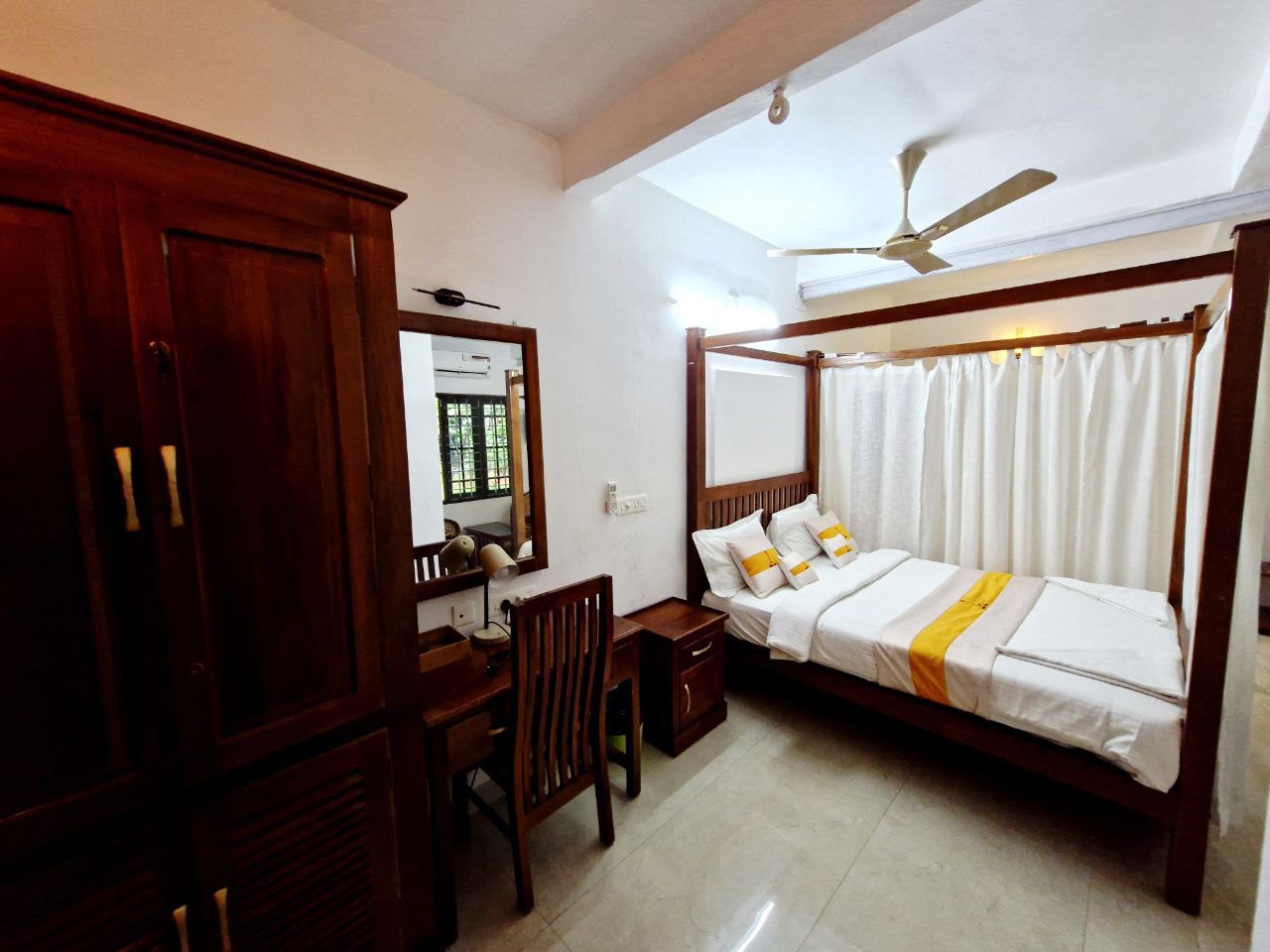 cozy bedroom in the best homestay in kochi,featuring modern wooden furniture, a comfortable bed